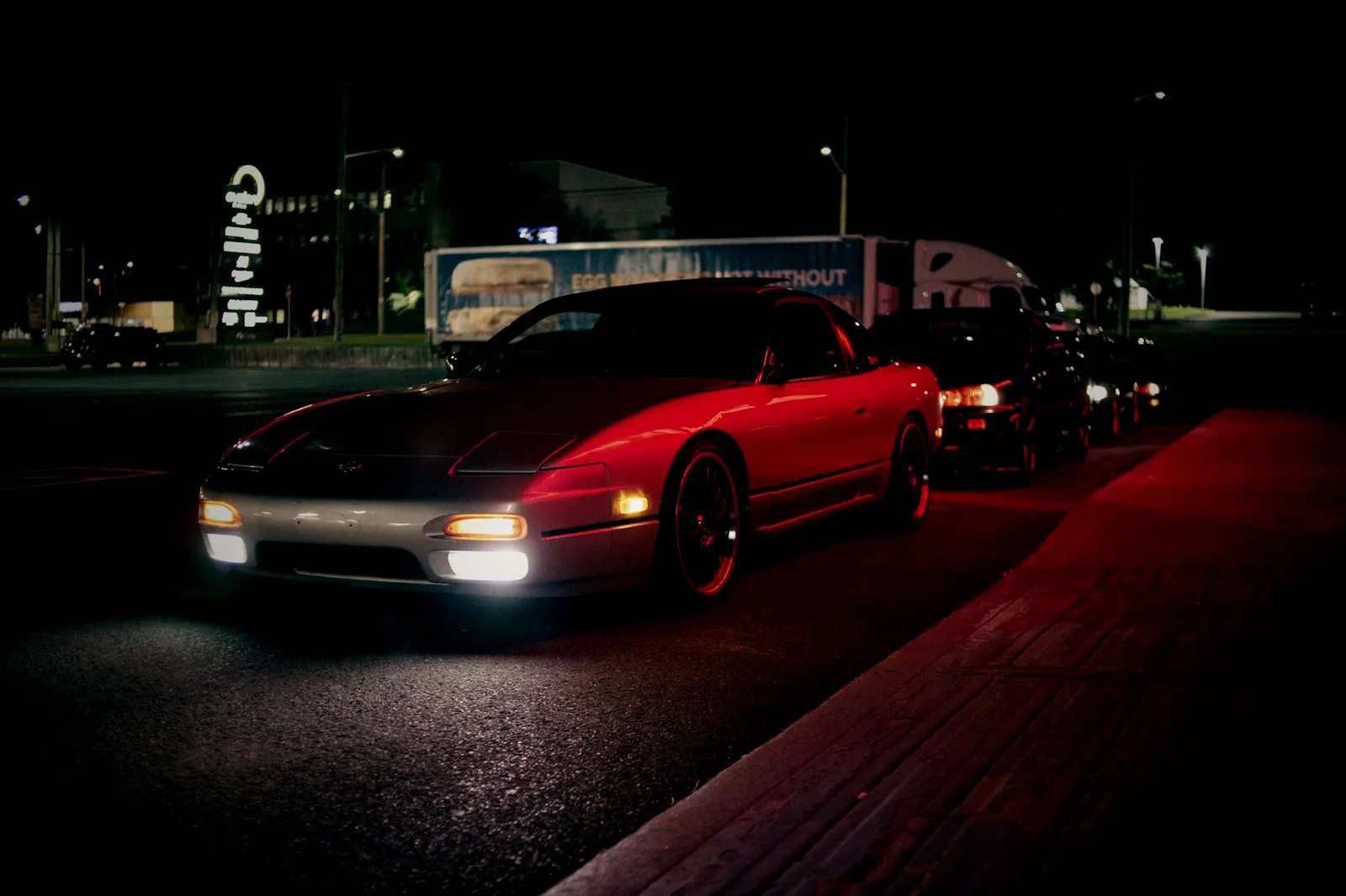 Red sports car under red light at night